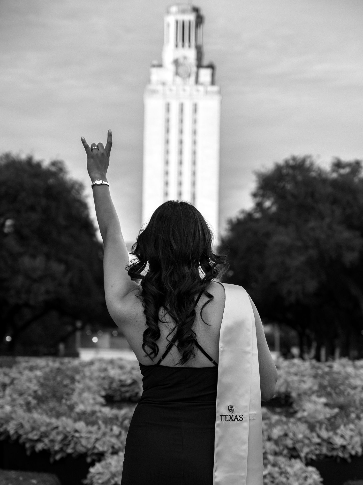 A black and white photo series showing a graduate in front of the University of Texas Tower making celebratory poses.