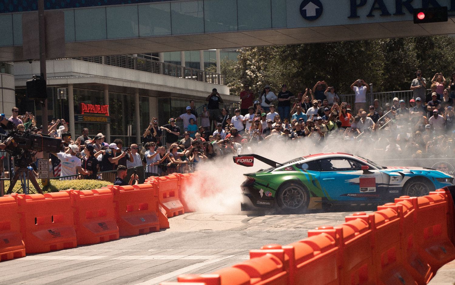 Formula 1 cars demonstrate high-speed runs through downtown streets lined with safety barriers and spectators.