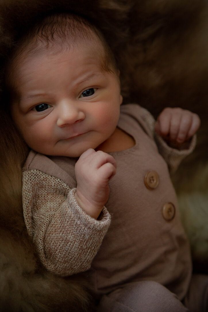 Indoor newborn photography session with baby boy in basket looking at camera in Omaha, Nebraska