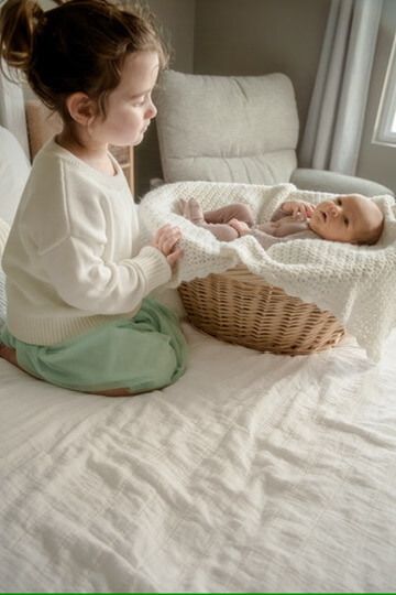 Indoor lifestyle family photography session with sister and newborn in Omaha, Nebraska