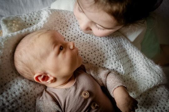 Indoor lifestyle family photography session with sibling and newborn in Omaha, Nebraska