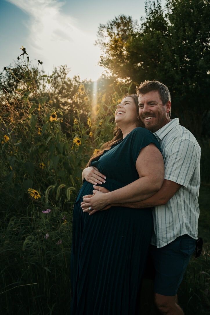 Outdoor family and maternity photography session during golden hour with expecting father and mother laughing in Omaha, Nebraska