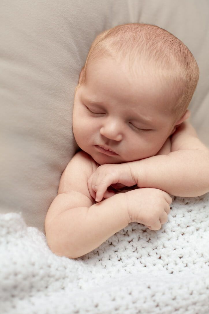 Baby girl asleep in white knit blanket from newborn lifestyle photography session in Omaha, Nebraska