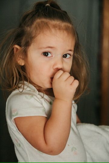 Indoor lifestyle family photography session with child sucking her thumb in Omaha, Nebraska