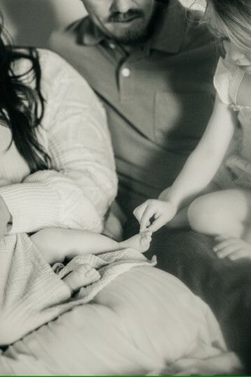 Indoor lifestyle family photography session with sister tickling newborn's toes in Omaha, Nebraska