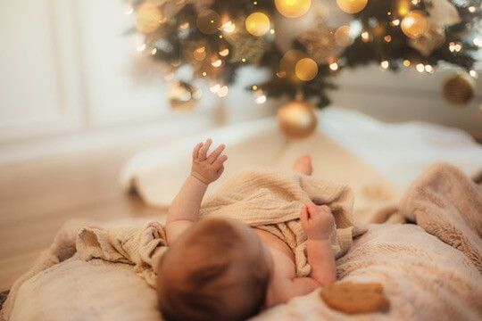 Indoor lifestyle family photography session with baby under Christmas tree in Omaha, Nebraska