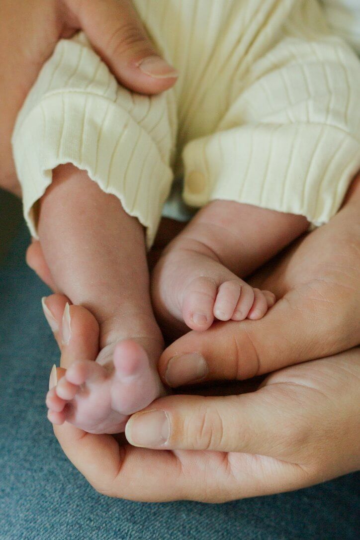 Baby girl feet in parents' hands from newborn lifestyle photography session in Omaha, Nebraska