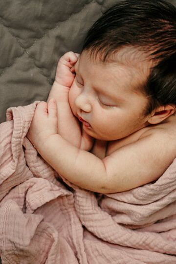 Baby girl in pink blanket from newborn lifestyle photography session in Omaha, Nebraska