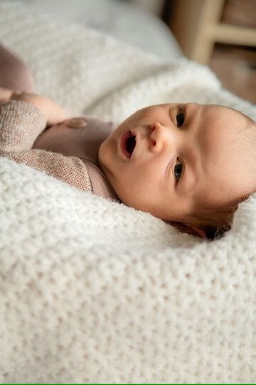 Baby boy in white knit blanket from newborn lifestyle photography session in Omaha, Nebraska