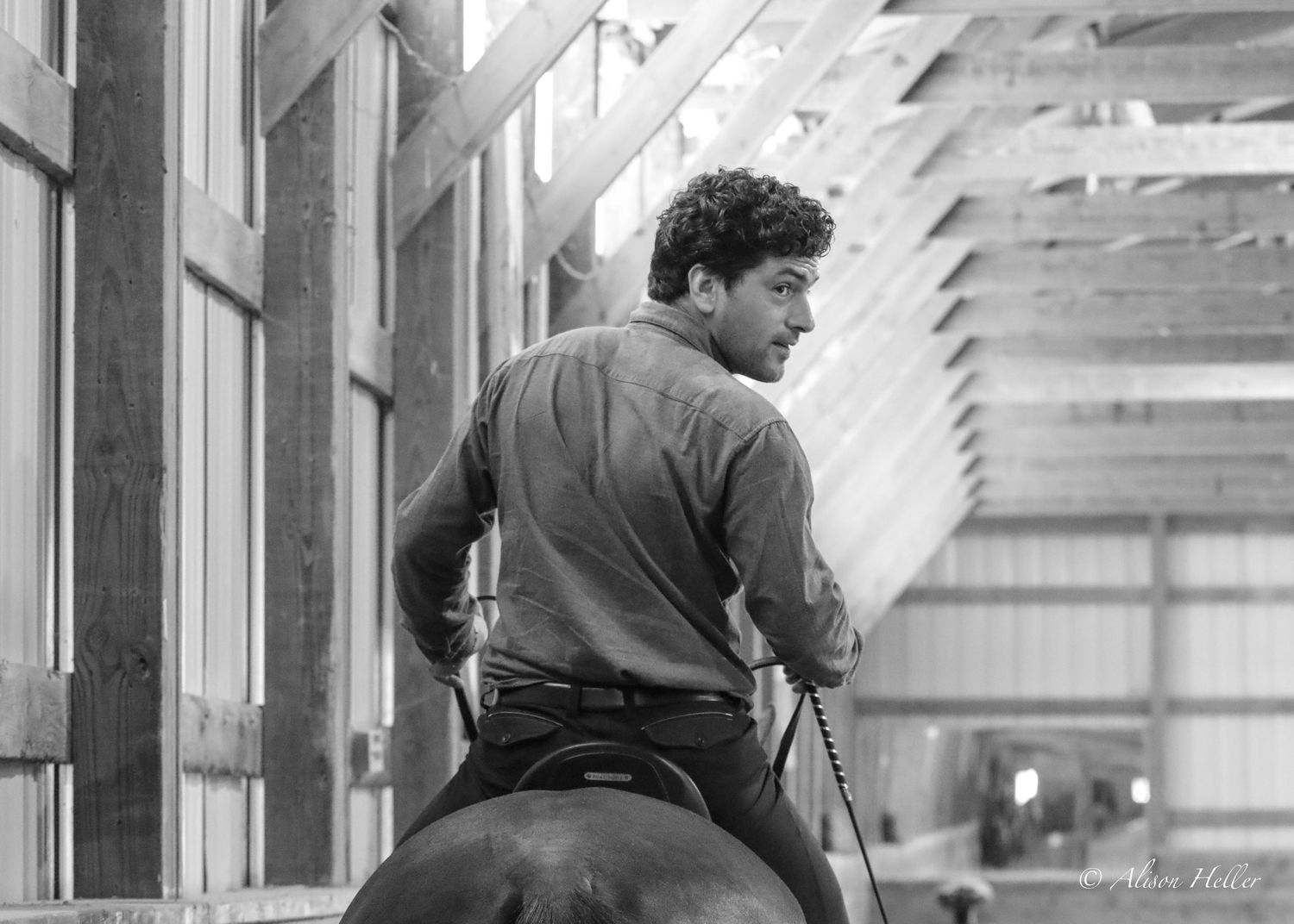 A black and white photo of a young man riding and looking back.