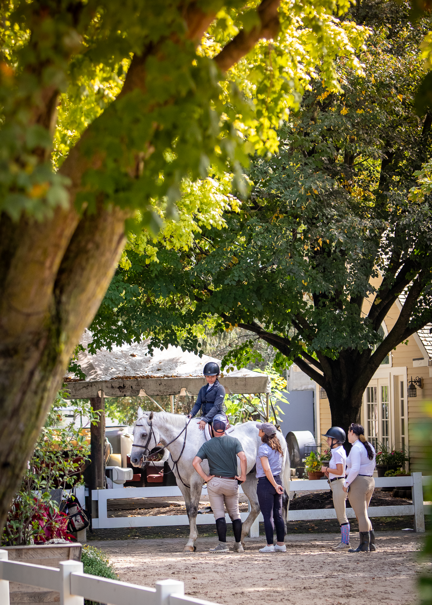 A group of equestrians group around a young girl on her horse at a horse show.