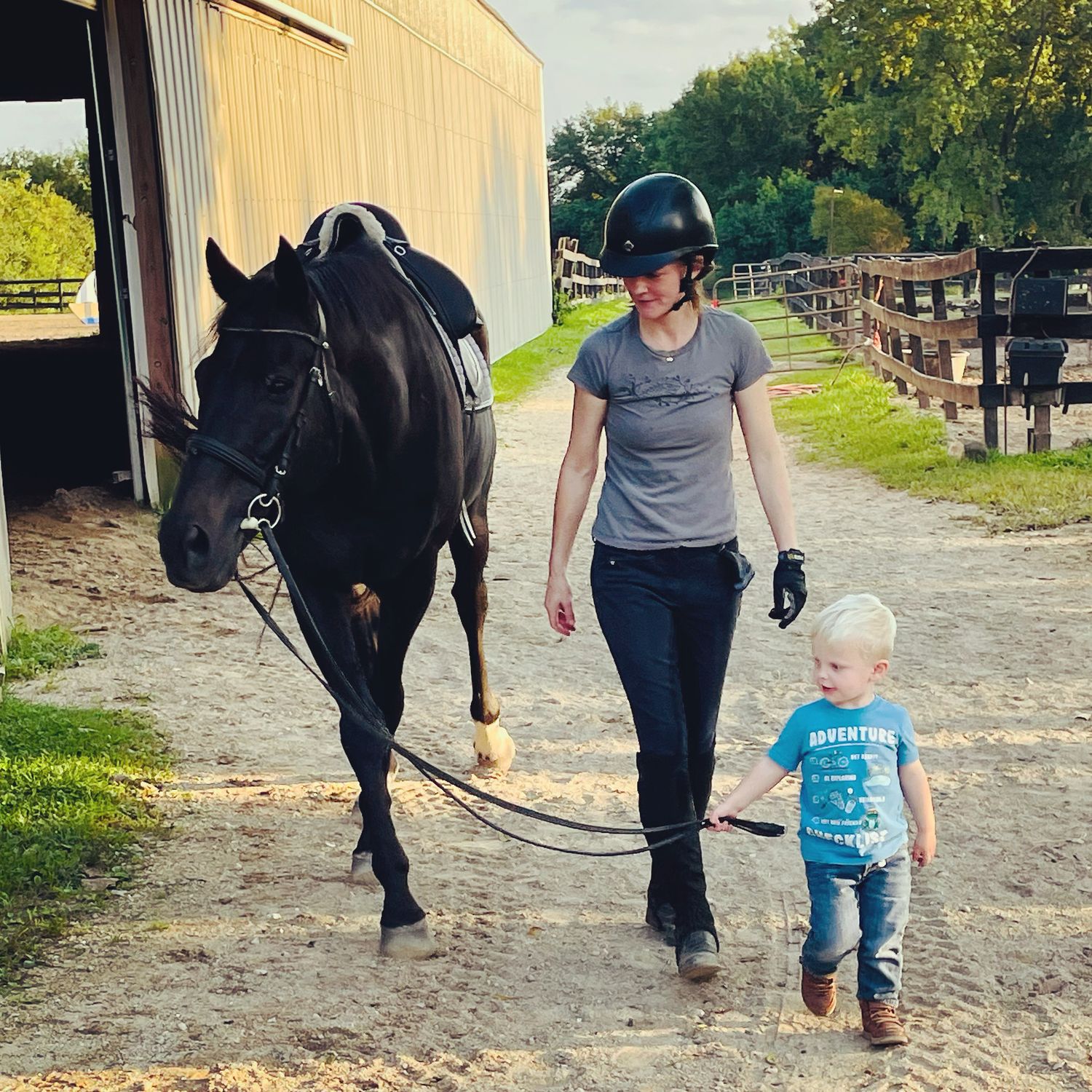 A horse, rider, and little boy walk toward the camera