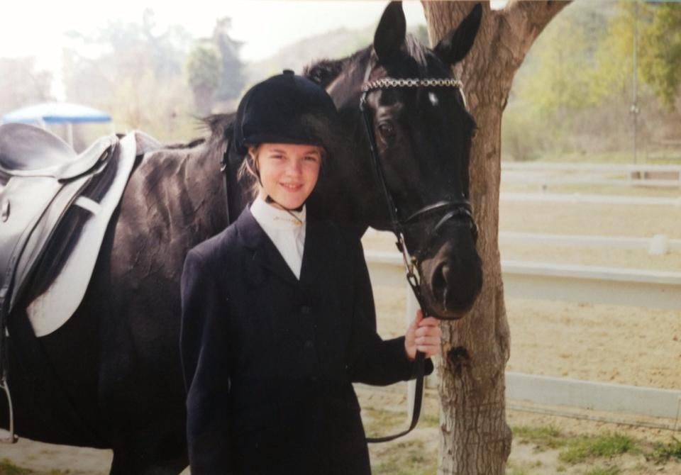 A young girl poses with her black mare.