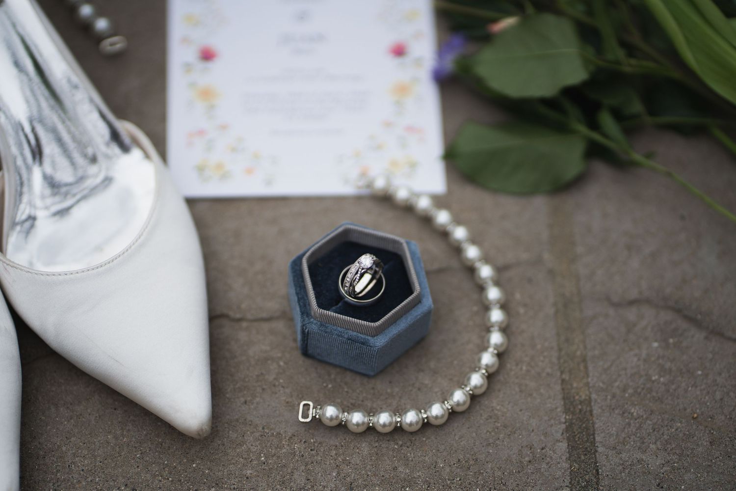 Wedding accessories including white shoes, rings, and jewelry arranged on a rustic surface.