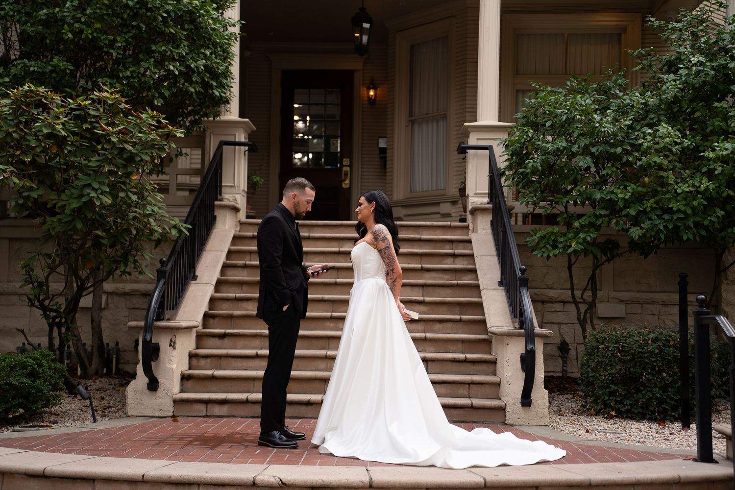 Wedding ceremony takes place on elegant stone steps surrounded by greenery.