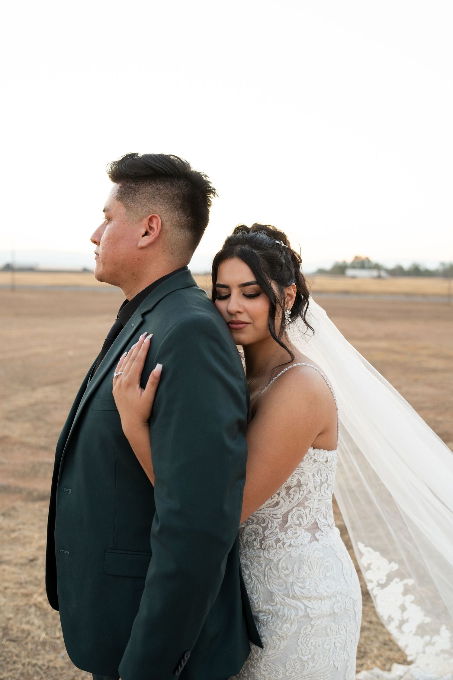Romantic outdoor wedding portraits in an open field at golden hour.