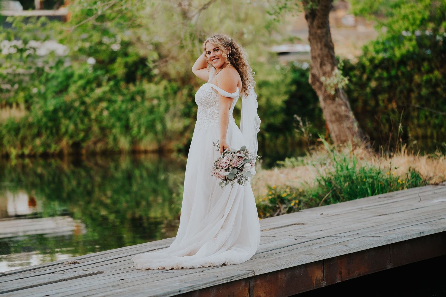 Elegant bride posing on wooden boardwalk surrounded by nature.