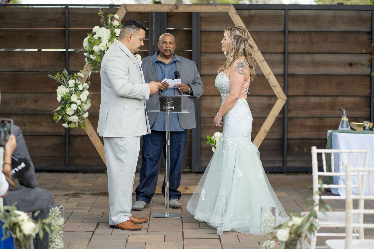 An outdoor wedding ceremony space with wooden walls and white decorative elements.