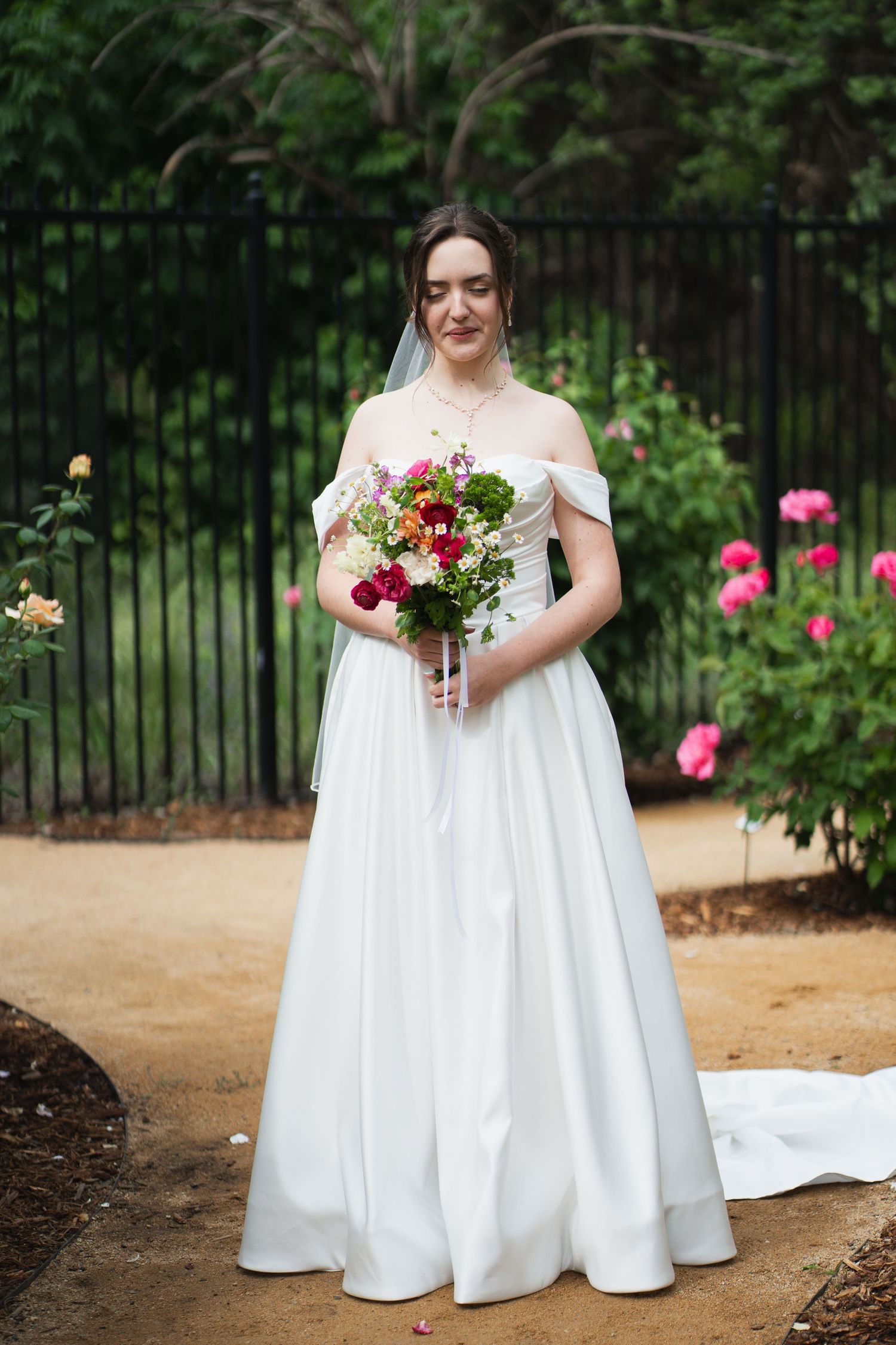 White wedding dress details with floral bouquet in a garden setting.