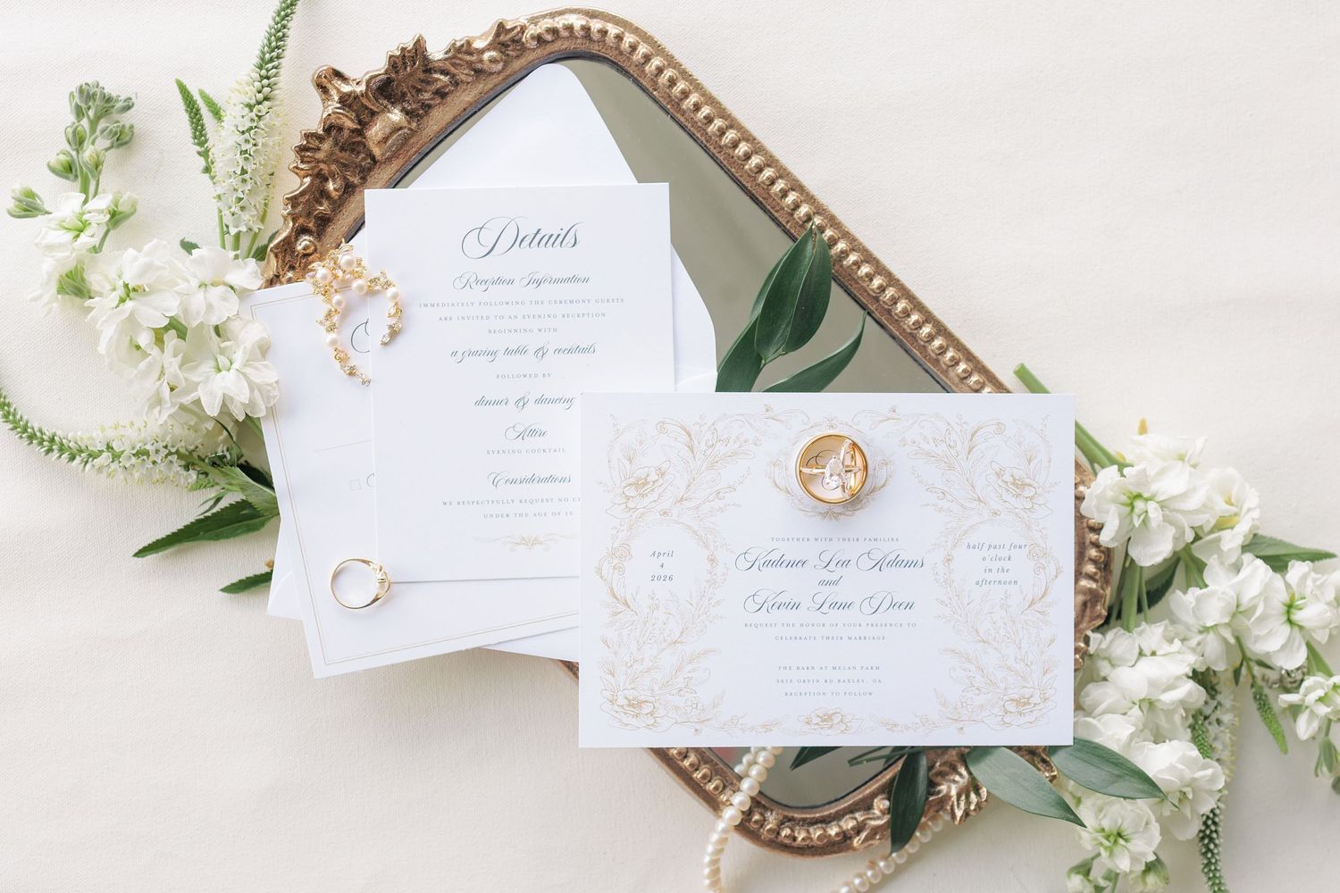 Editorial detail shot of a flat lay with wedding invitations, rings, and florals at a South Georgia venue.