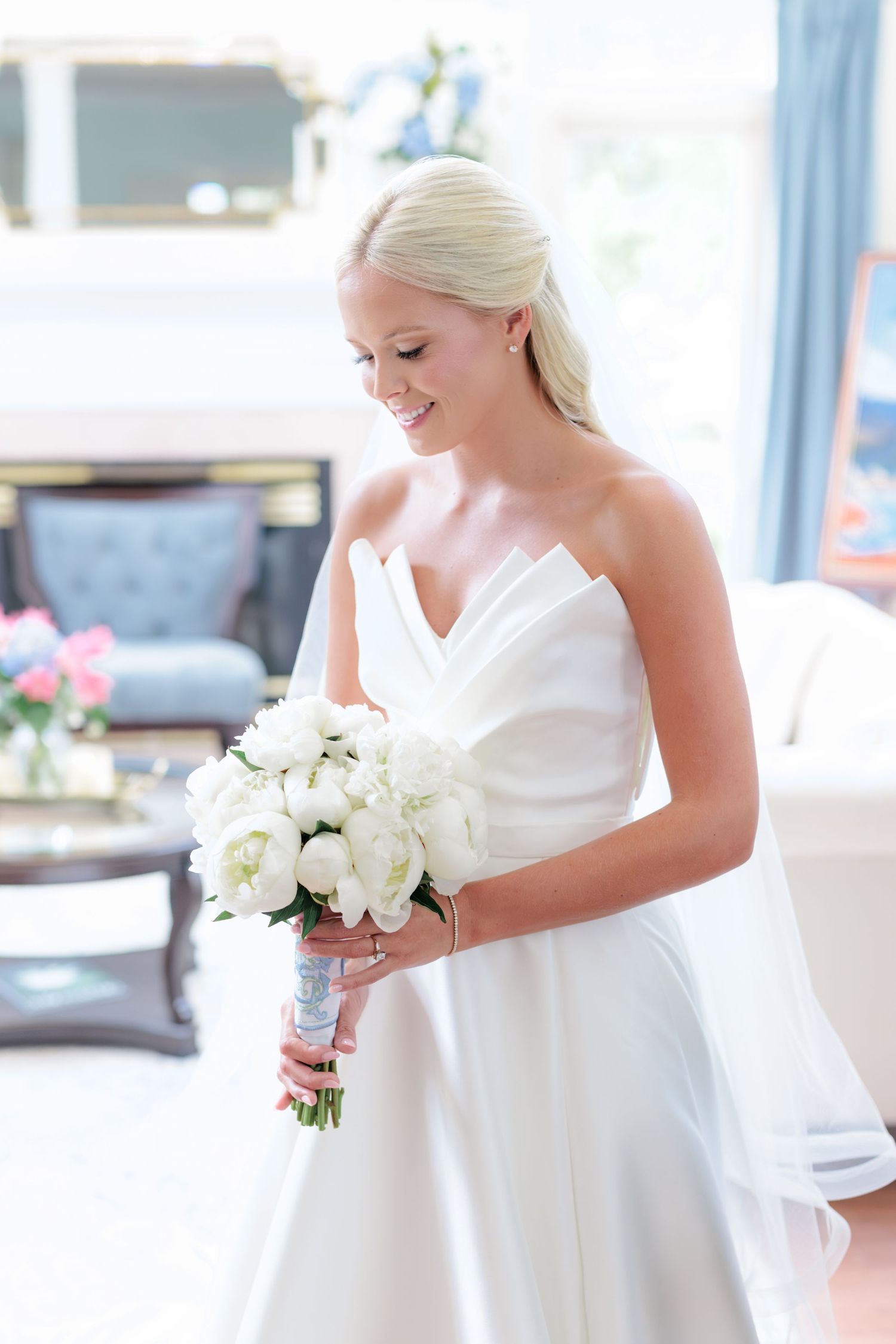 Bride admiring her floral bouquet after she puts on her wedding dress and reflecting on the day. Taken by a photographer based in Valdosta.