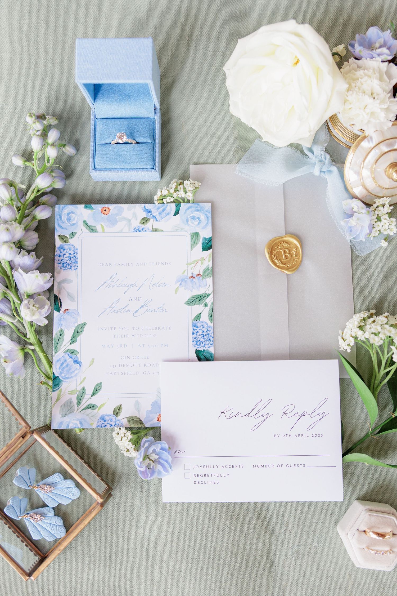 Editorial detail shot of a flat lay with wedding invitations, rings, and florals at a South Georgia venue.