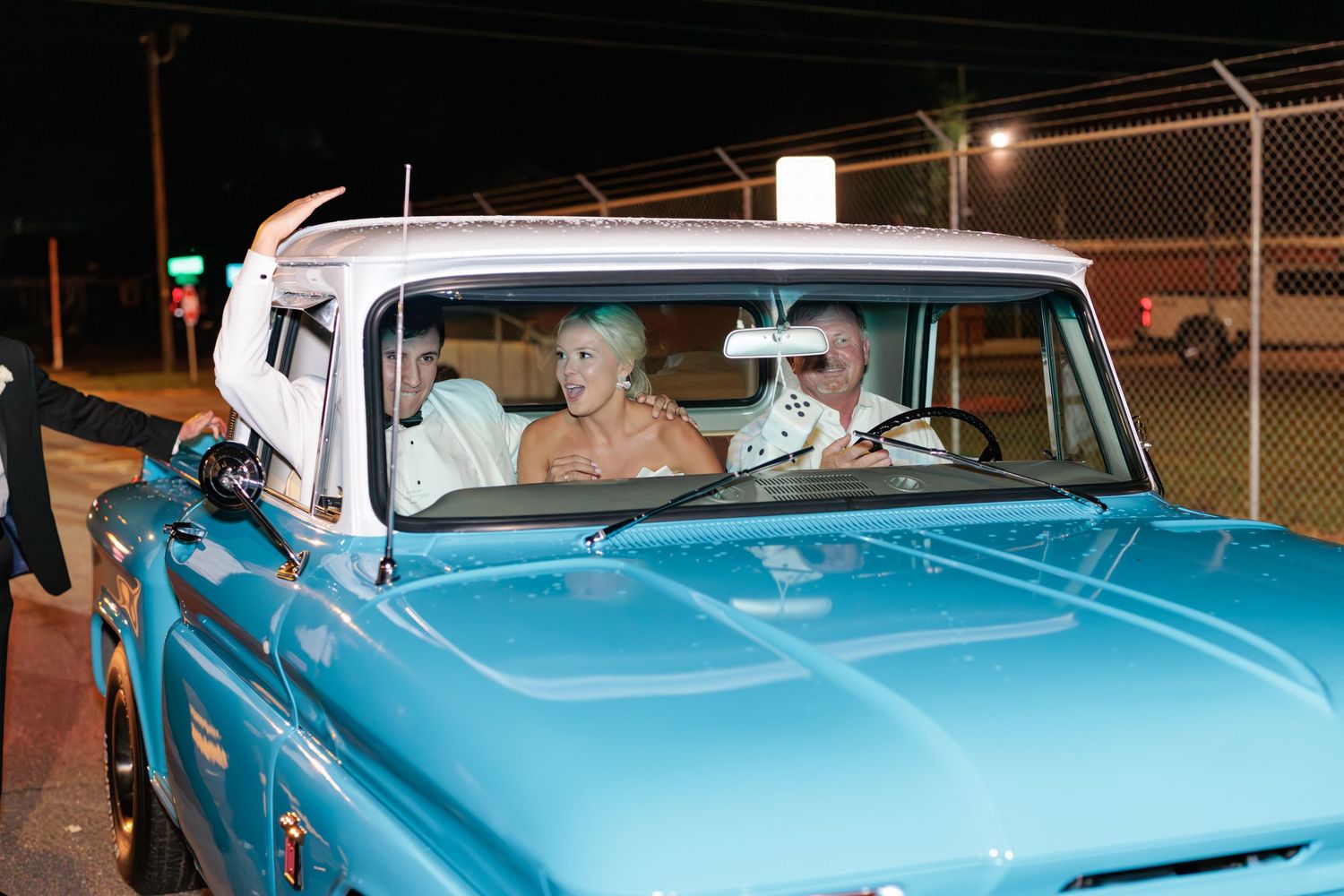 Couple in their getaway vehicle as they wave goodbye to all their friends and families that attended their wedding ceremony and reception.