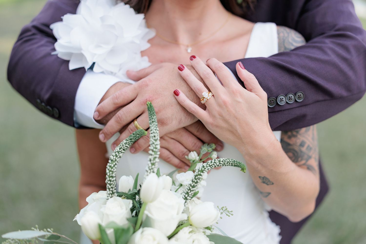 Couple embracing in their wedding attire, highlighting their rings and floral arrangement in South Georgia.