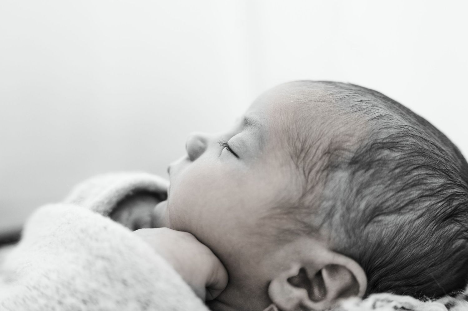 Newborn baby side profile, wrapped and resting during studio session in Katy, Texas.