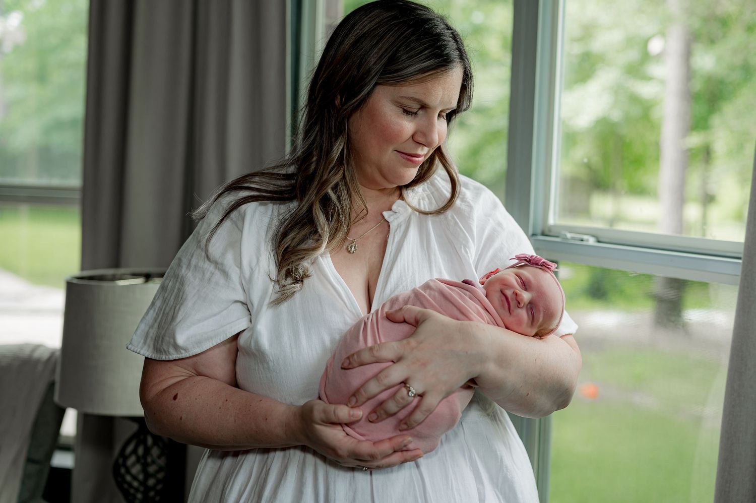 Lifestyle Newborn Session with smiling newborn in the arms of her mother in Houston, Texas.