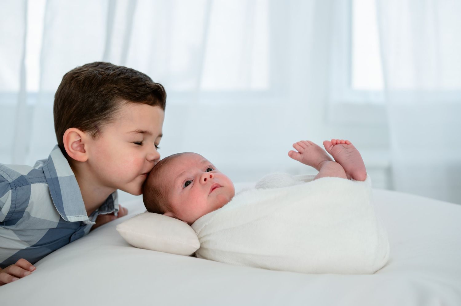 Big brother kissing baby brother's head in studio session Katy TX.