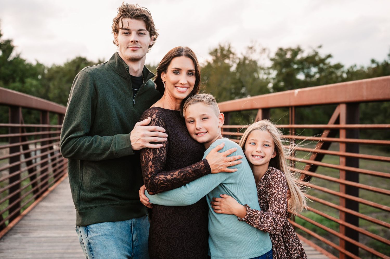 A mother hugging her kids for mommy and me portrait at their family photography photoshoot in Katy, TX outdoors on a bridge.