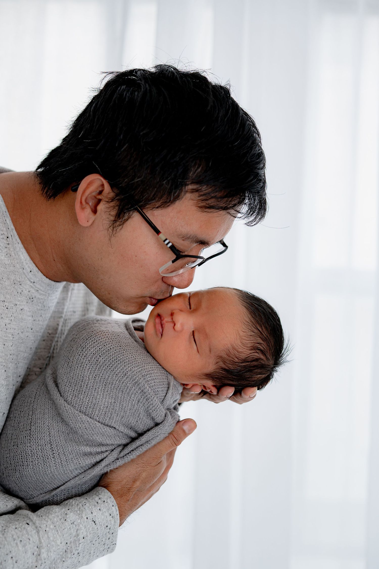 Dad kissing newborn during timeless studio newborn session Houston Tx