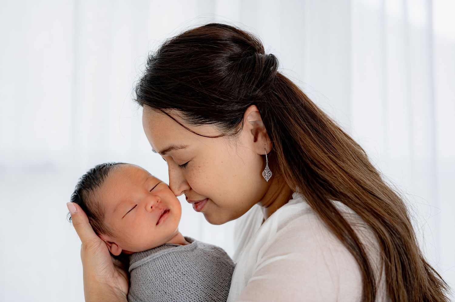 Timeless newborn studio session with mom snuggling with baby in Fulshear TX