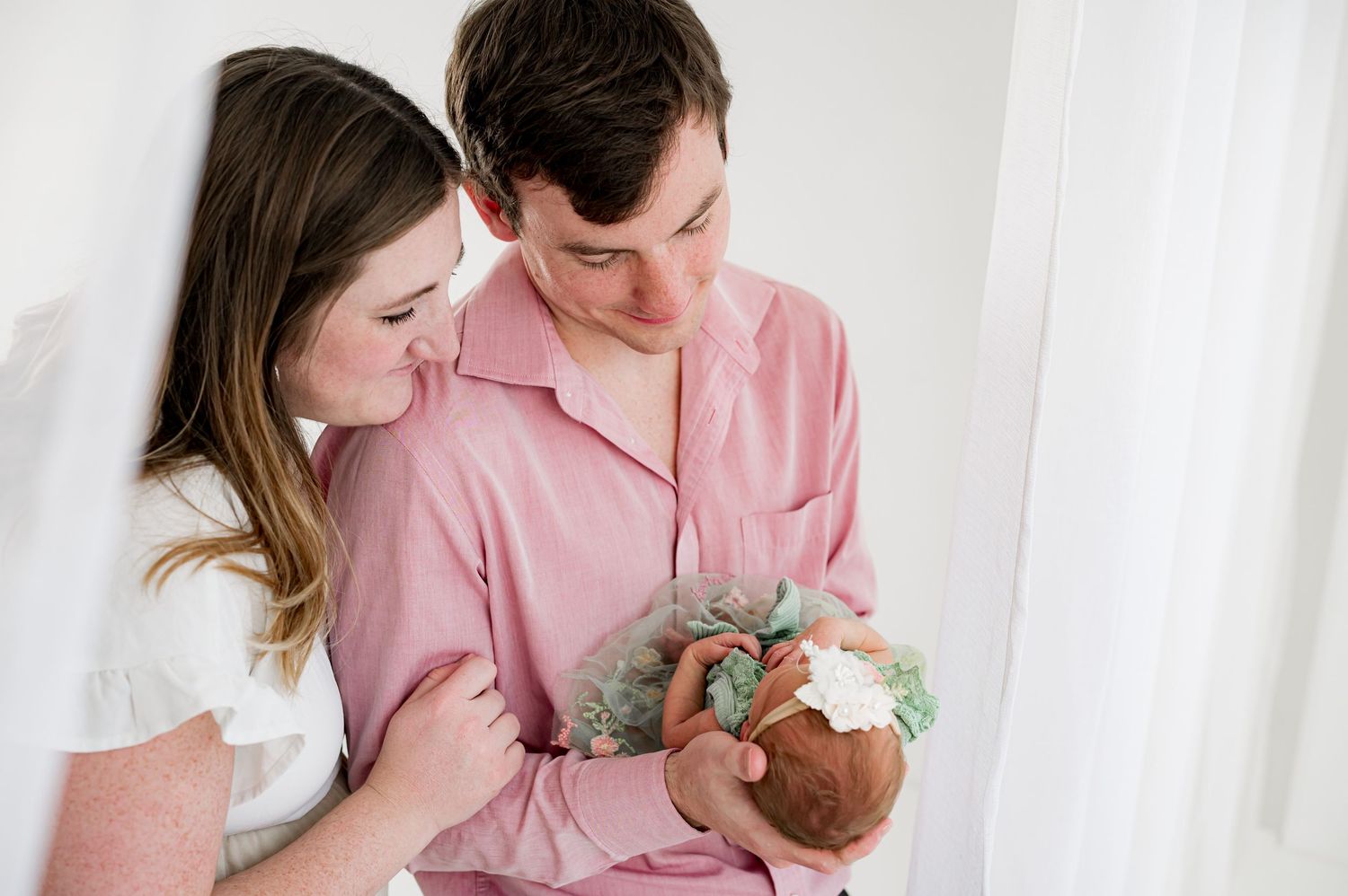 Parents holding their newborn baby during a light and airy studio session in Fulshear, Texas.