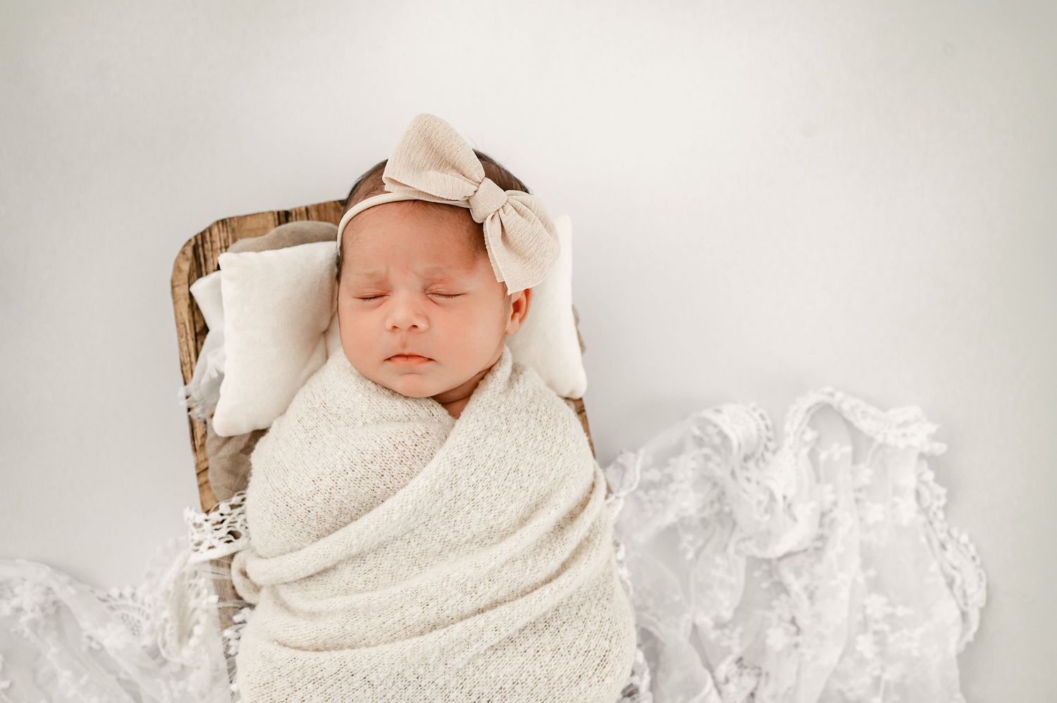 Sleeping newborn baby girl wrapped in neutral tones in a Fulshear, Texas studio session.