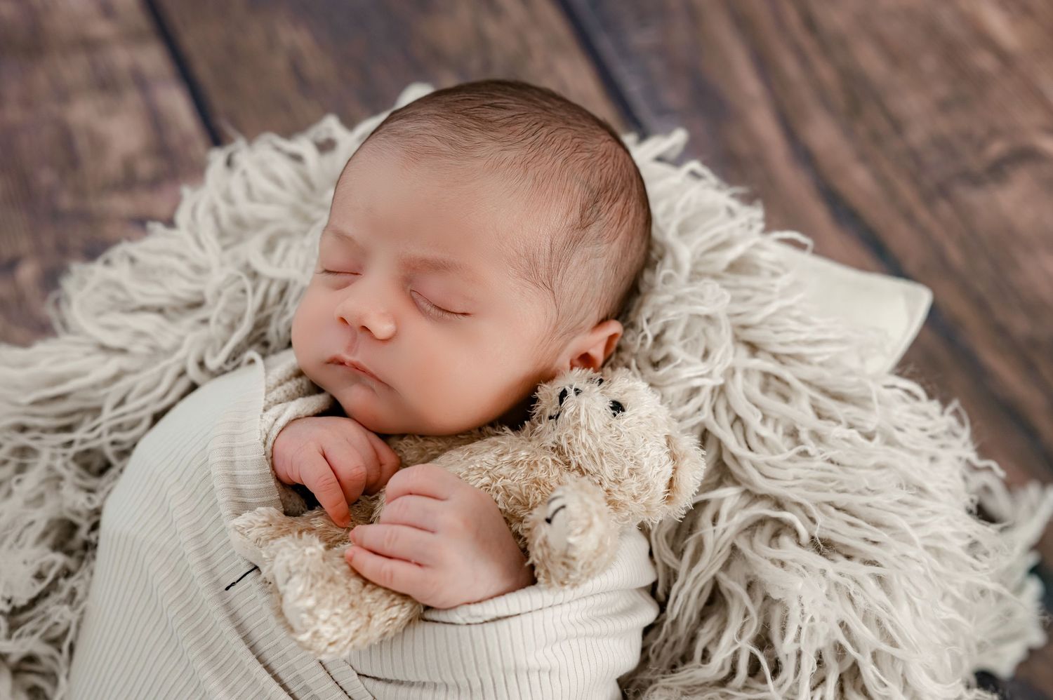 Newborn baby wrapped in neutral tones with teddy bear during Katy Newborn photography session.