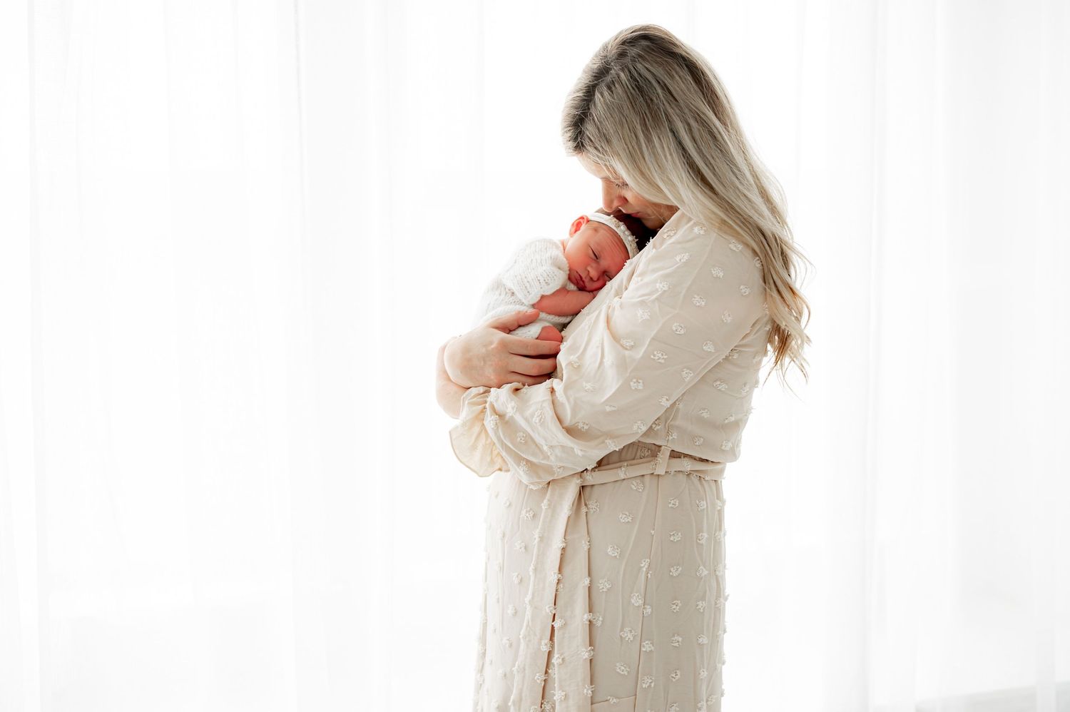 Mom snuggling baby in a neutral baby-led session Katy TX