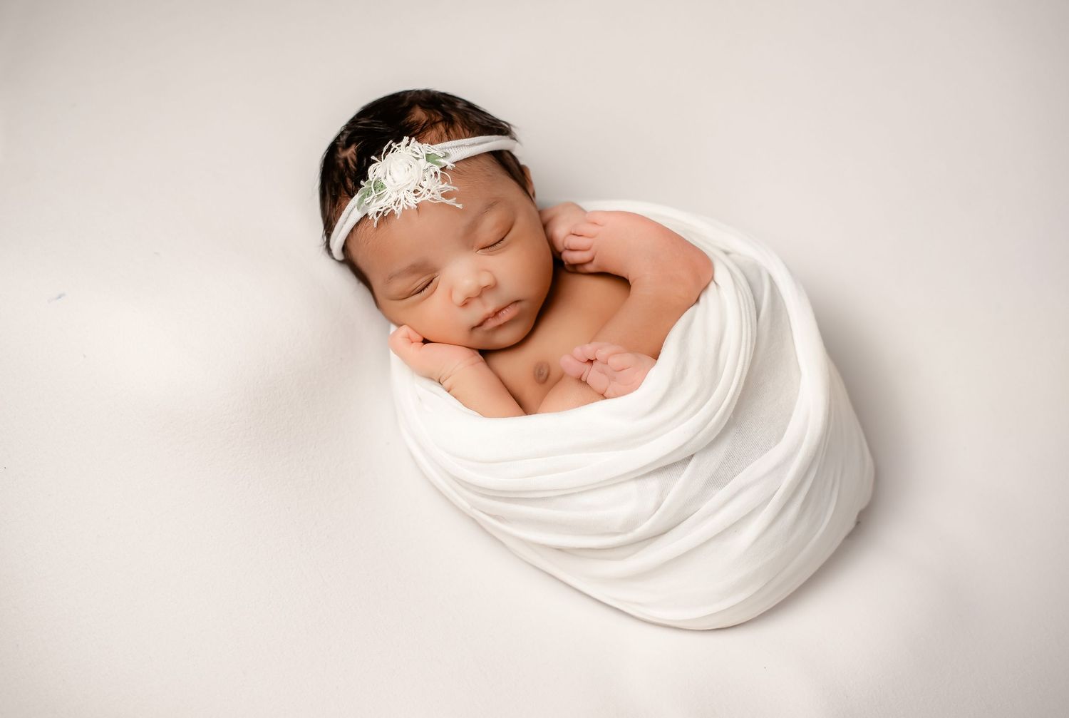 Wrapped sleeping newborn baby in neutral tones in Katy TX studio session