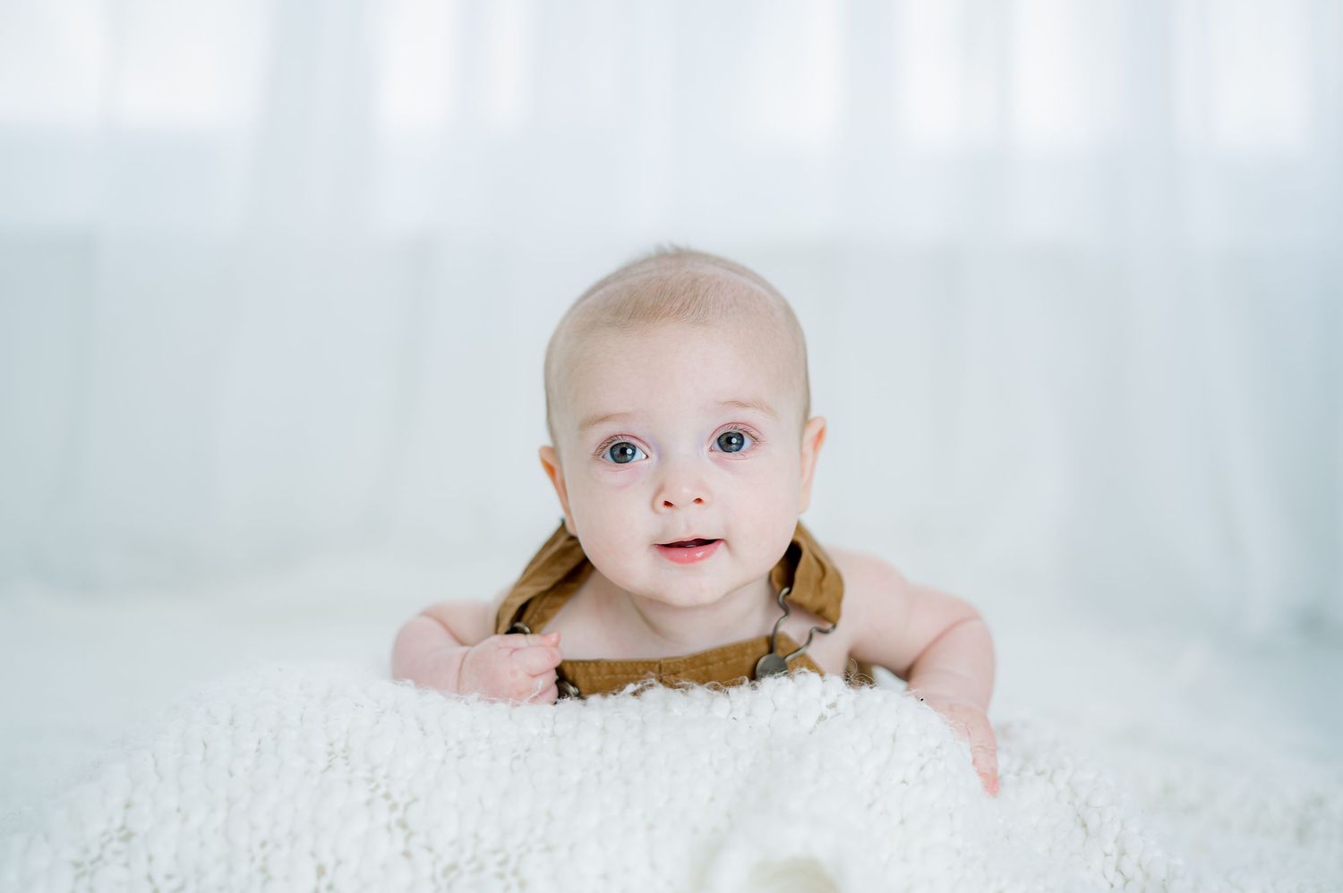 Tummy time milestone session in Katy, TX with a smiling baby boy.