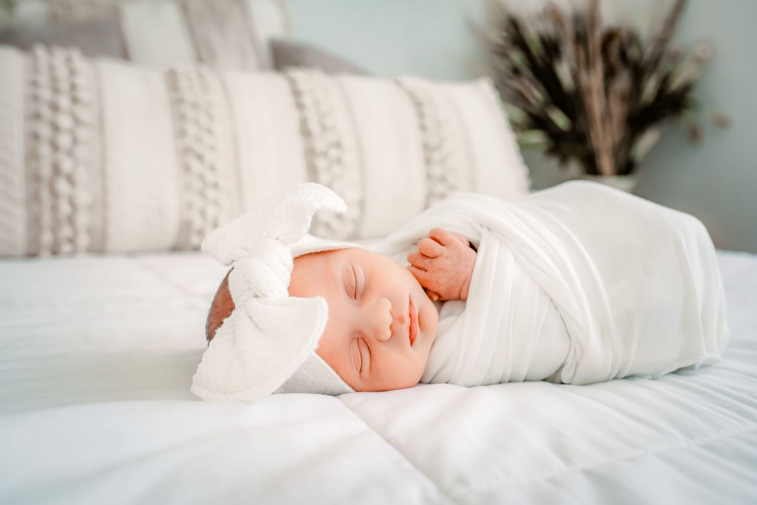 Newborn baby lying on white bed during a natural lifestyle session in Katy, Texas.