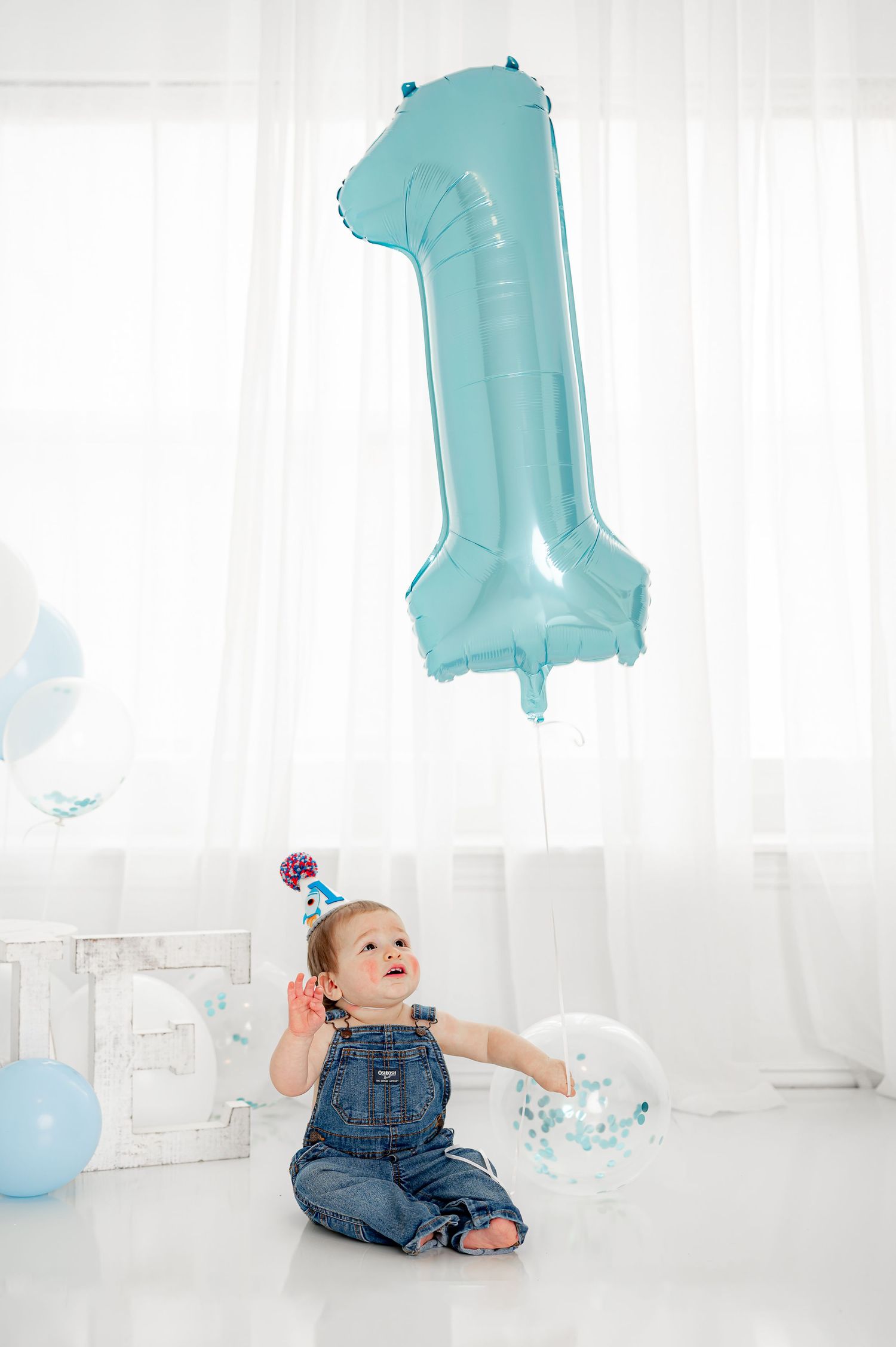 Baby boy holding one year balloon during his Katy Milestone Birthday Session