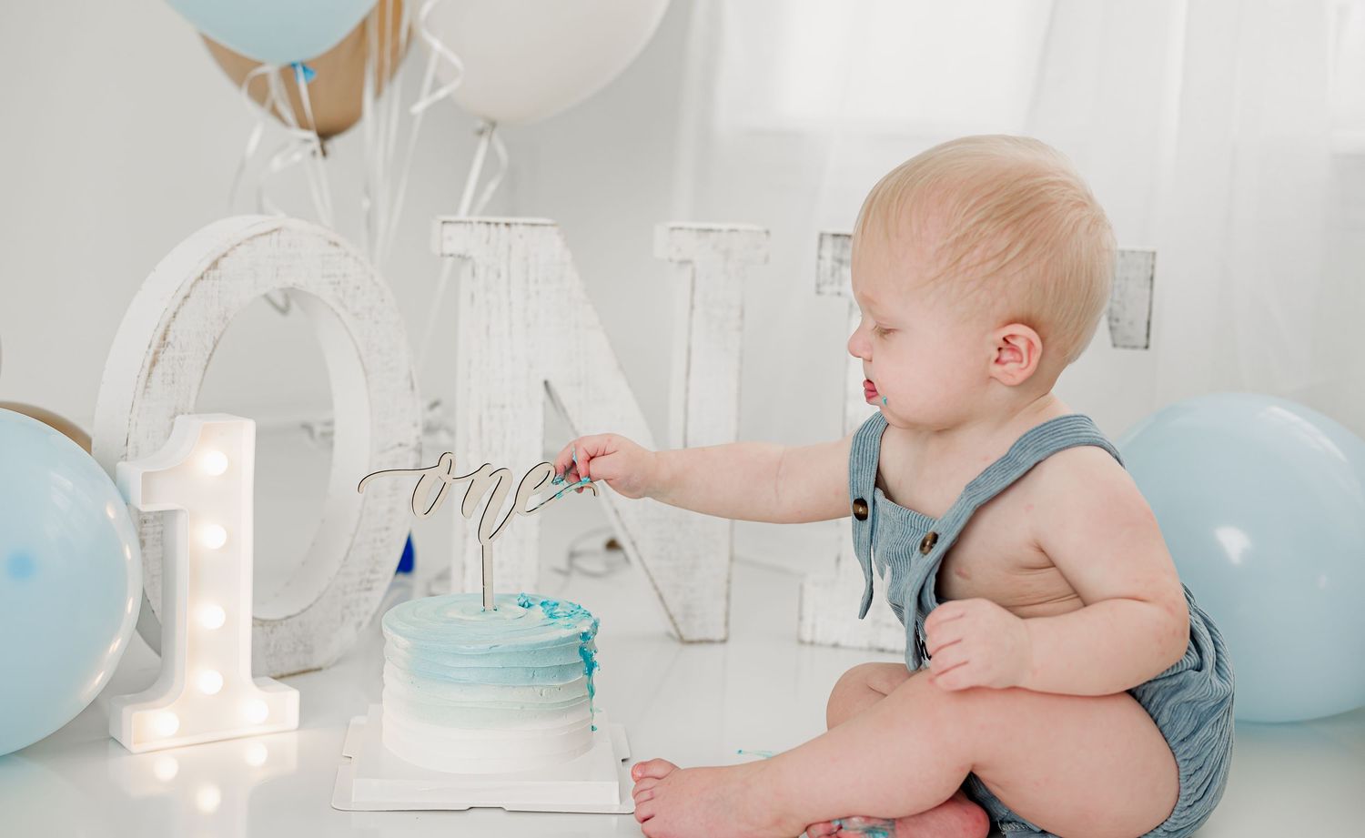 Cake smash session in Fulshear, TX with sweet baby boy checking out his cake.