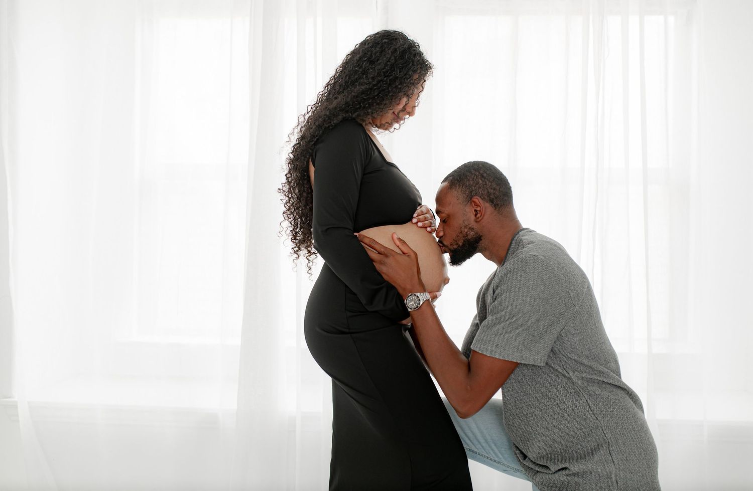 Expecting mother with partner embracing mom's baby bump during a Katy, TX studio session.