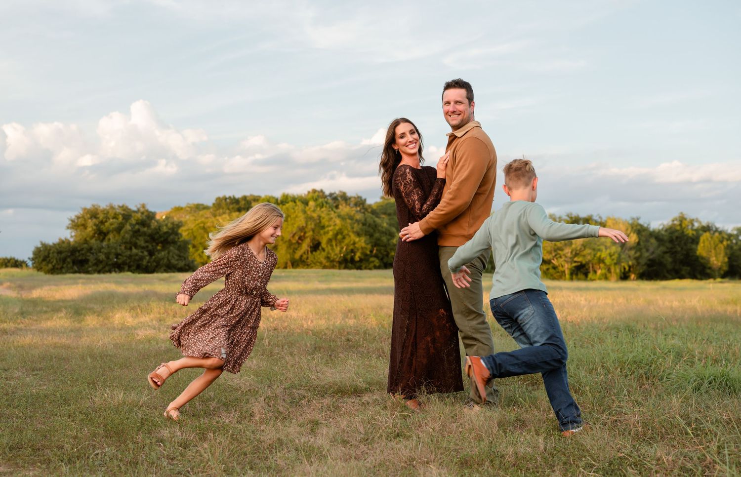 Kids running around their parents in an open field in the Firethorne community in Katy, TX.