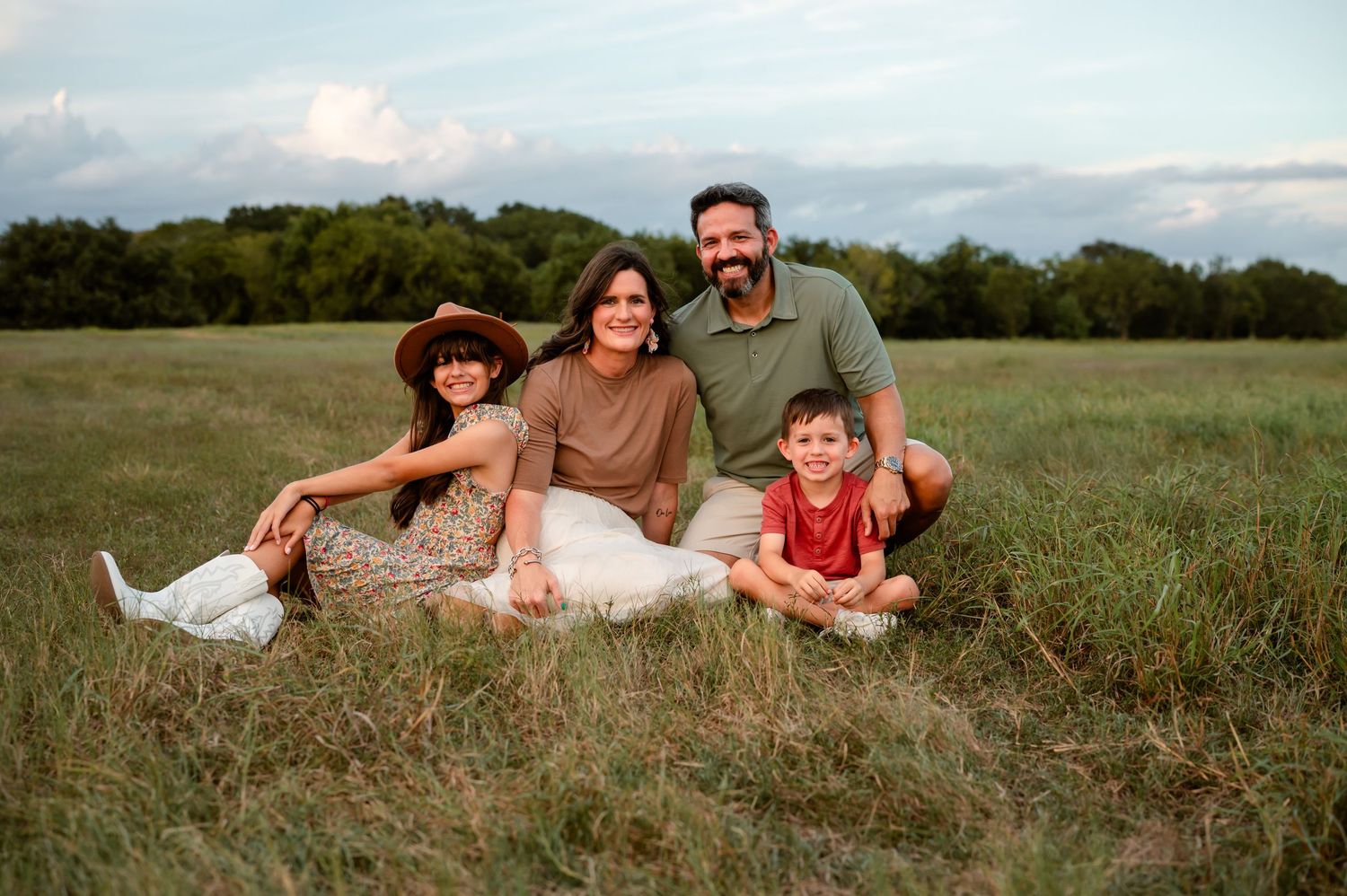 A family sitting in an open field during their family photography session in Katy, TX.
