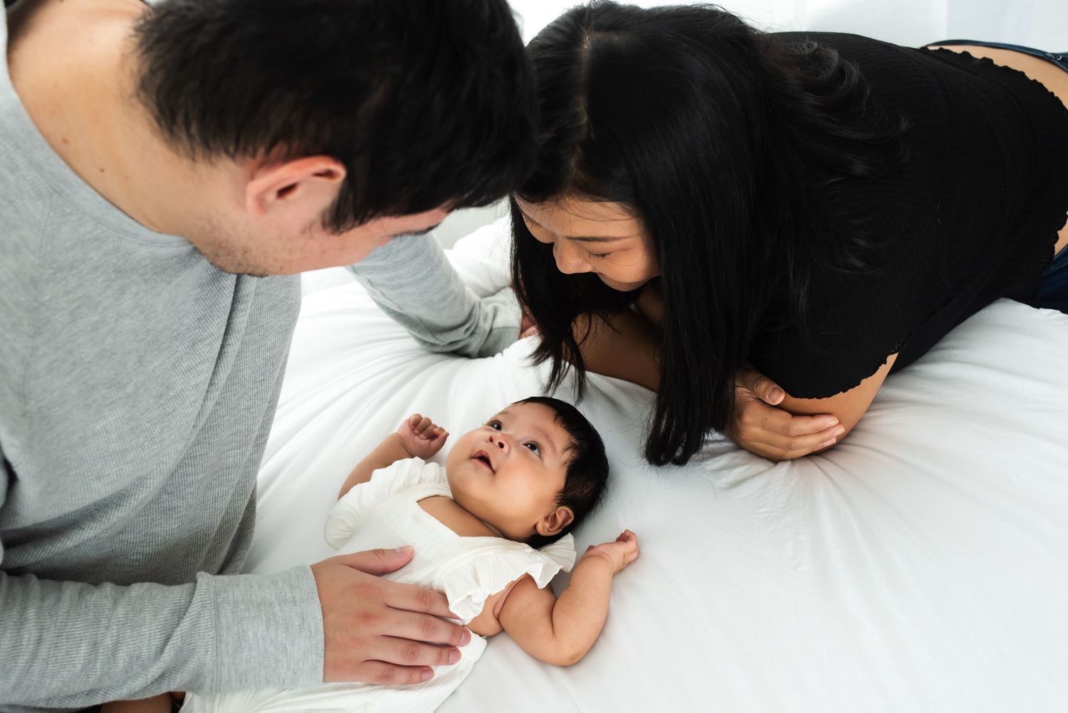 Parents and baby gazing at each other in a relaxed newborn session Katy, TX