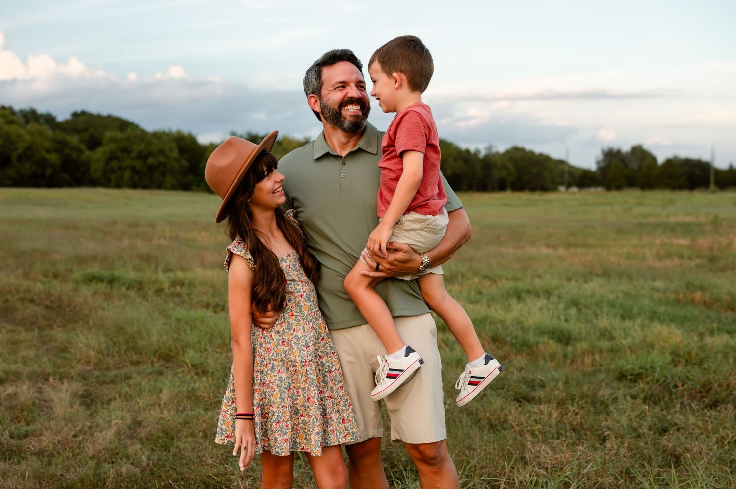 A father laughing with his kids at their family photography session in a open field in Katy, TX.