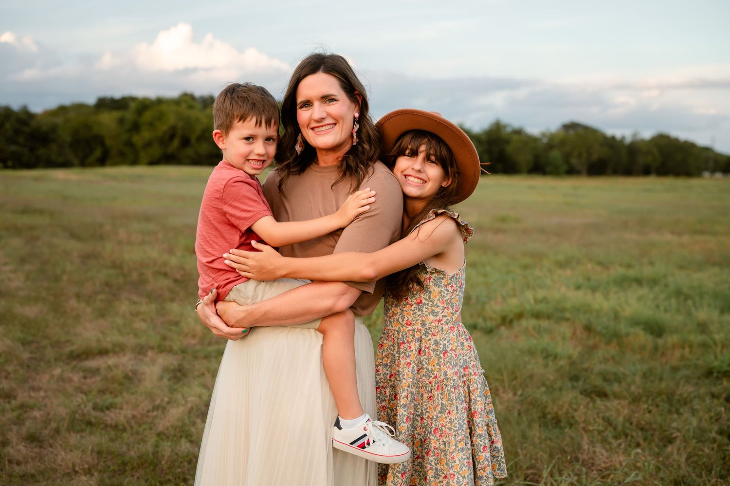 A mother snuggling her kids in an open field for her Katy, TX family photography session.
