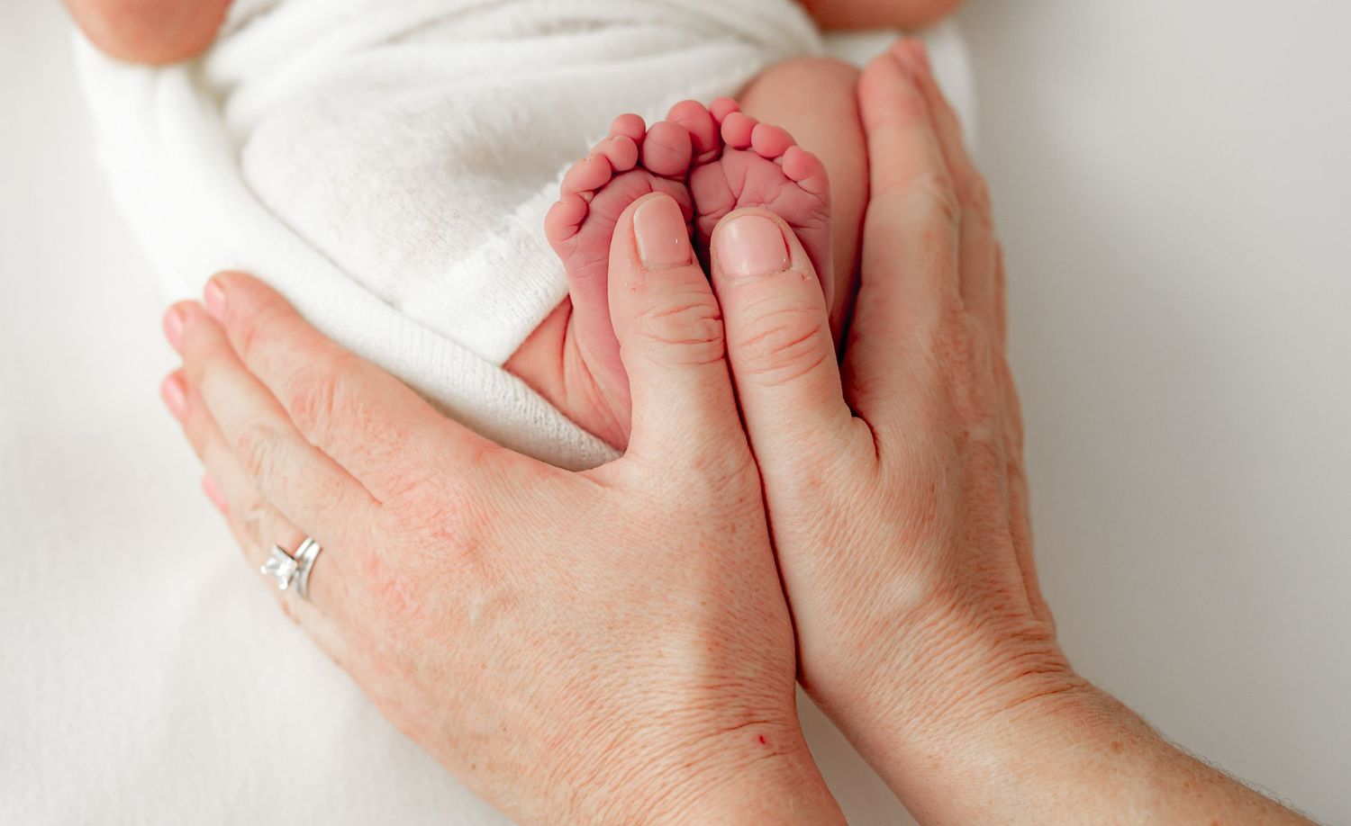 Close- up of newborn feet gently held by their parents hands.